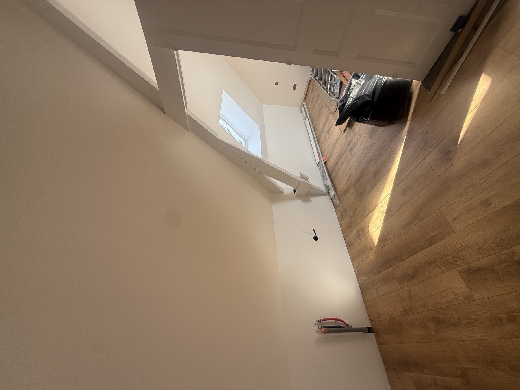 Parquet posé sous les rampants Vue d'ensemble d'une pièce mansardée avec parquet aspect bois et fenêtre de toit par Aristopeintre